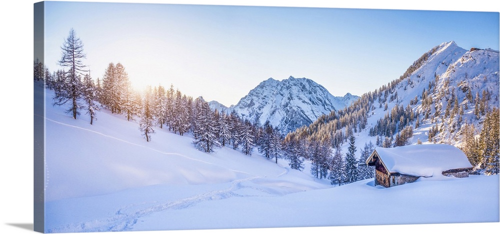 Panoramic view of beautiful winter wonderland mountain scenery with traditional mountain cabin in the Alps in golden eveni...