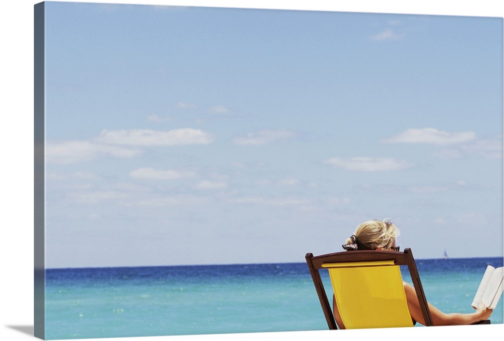 Woman at beach reading in chair