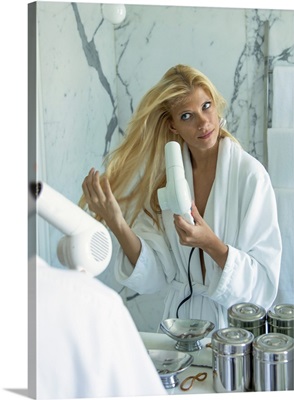Woman blow drying her hair in bathroom