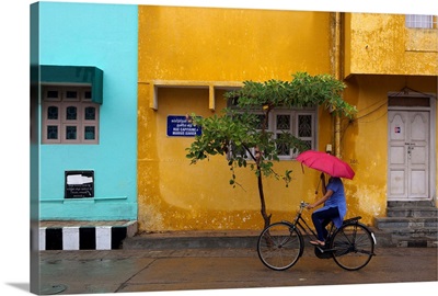 Woman cycling in Pondicherry street with umbrella.