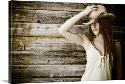 Woman in cowboy hat posing by wall