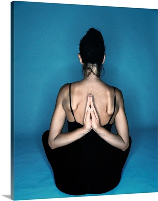 Woman sitting in yoga reverse prayer position