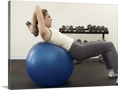 Woman using exercise ball and hand weights
