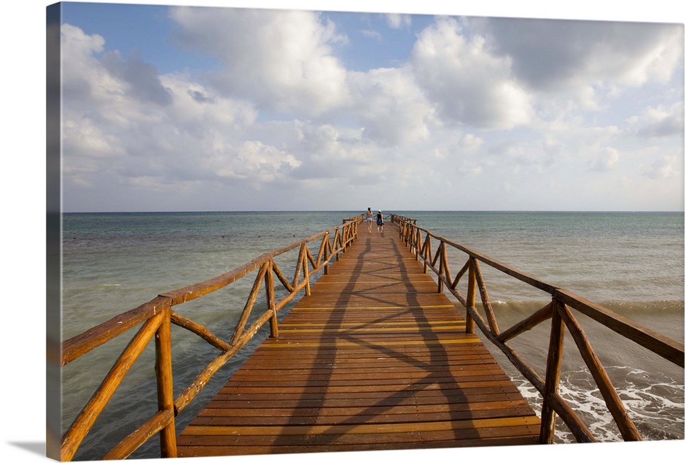People on rustic wood pier leading to Caribbean Sea horizon, Cancun, Mexico