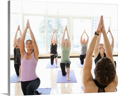 Yoga instructor leading class through the Anjaneyasana (Low Lunge Pose)