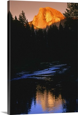 Yosemite's Half Dome looms over the forest surrounding the Merced River