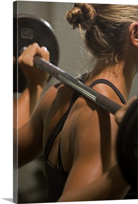 Young woman exercising with barbell