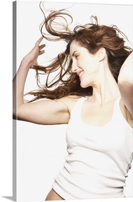 Young woman in white tank top tossing hair