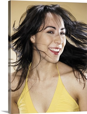 Young woman tossing hair, smiling, portrait, head and shoulders
