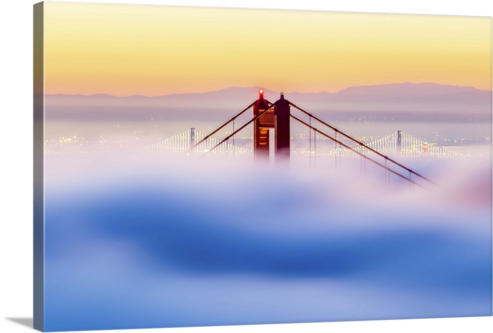 A dynamic photograph of the golden gate bridge just barely making it above a thick blanket of clouds.