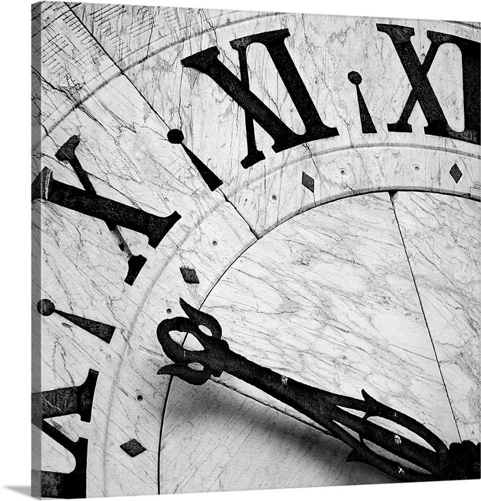 Square black and white photograph of the details of a clock, focusing on the hands and numbers.
