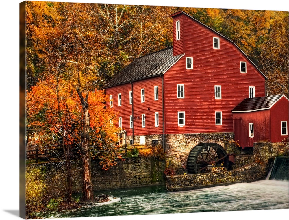 A Photograph of an old rustic looking watermill. With rushing water in the foreground.