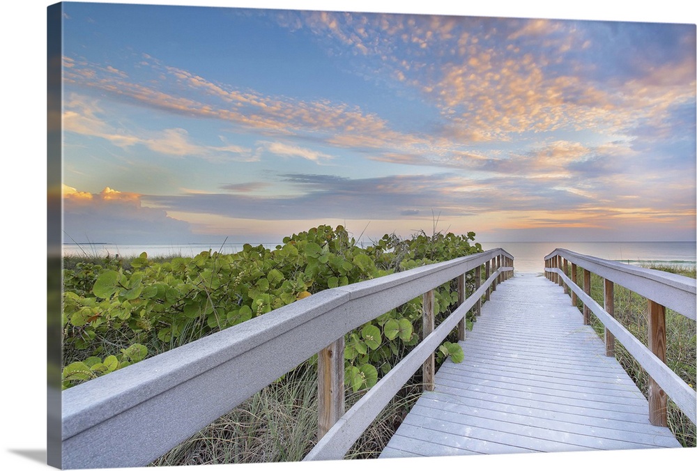 A boardwalk on Sunset Beach leads towards a stunning sunset near Treasure Island in Florida.