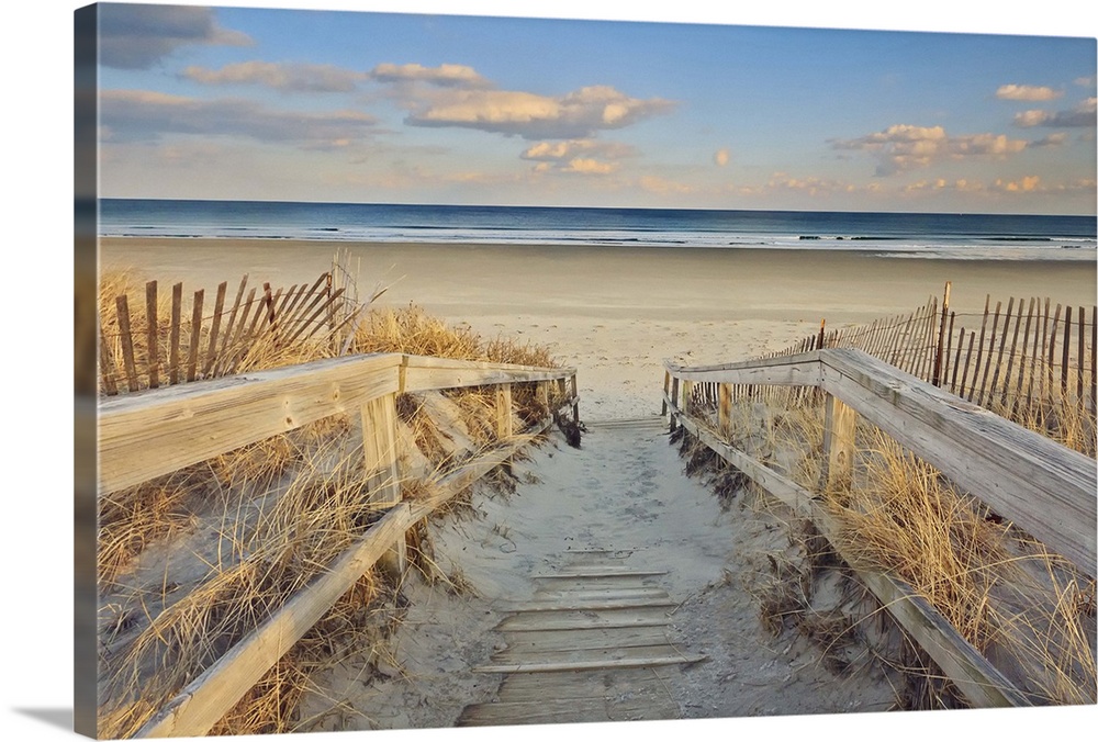A photograph of an idyllic scene with a wooden walkway leading down to a sandy secluded beach.
