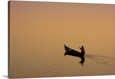 A fisherman paddling across Taungthaman Lake at sunrise, Amarapura, Myanmar