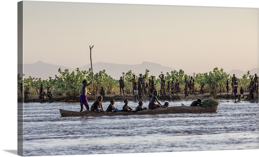 A large dugout canoe ferries Dassanech people across the Omo River in the late afternoon, Ethiopia.