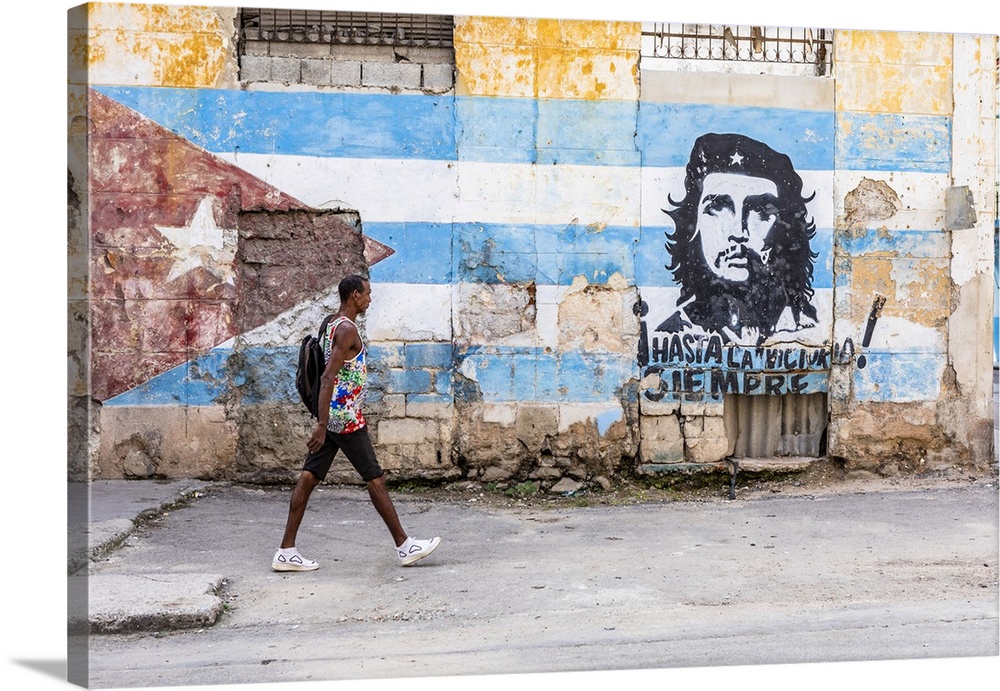 A man walking in a front of Che Guevara street art in La Habana Vieja (Old Town), Havana, Cuba