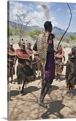 A Pokot warrior jumps high in the air surrounded by women to celebrate an Atelo ceremony