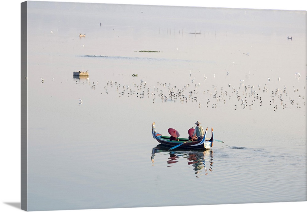 A rowing boat surrounded by birds carries two novice monks towards U-Bein bridge on Taungthaman Lake, Amarapura, Mandalay,...