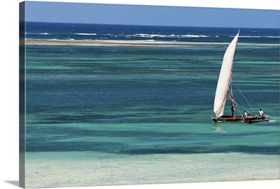 A traditional outrigger canoe sails close to the shore at Diani Beach