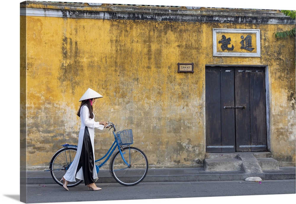 A Vietnamese girl cycles past a colonial building in Hoi An Ancient Town, Hoi An, Quang Nam Province, Vietnam.