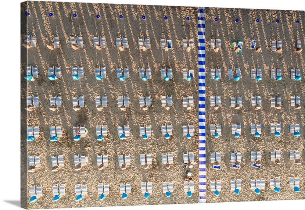 Aerial view of white sunbeds in a row on empty sand beach in summer, Vieste, Foggia province, Gargano, Apulia, Italy.