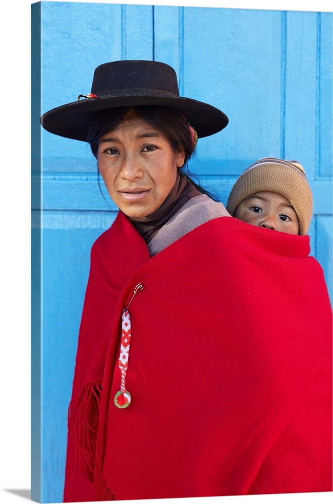 Portrait of an Aymara mother in traditional clothes with her child standing in front of the antique church of Aparzo, Juju...