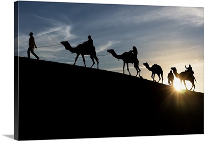Berber Silhouette At The Sunset In The Sand Dunes With Dromedary, Sahara Desert, Tunisia