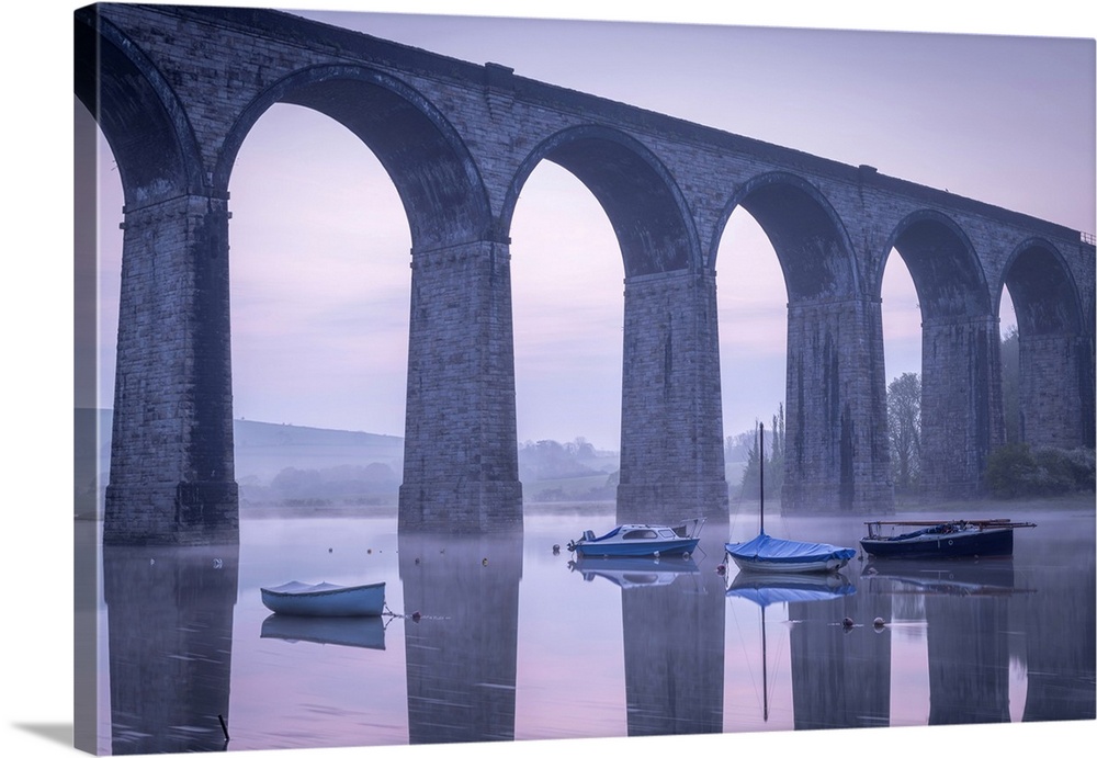 Boats beneath St Germans Victorian viaduct at dawn, St Germans in Cornwall, England.  Spring (April) 2022.