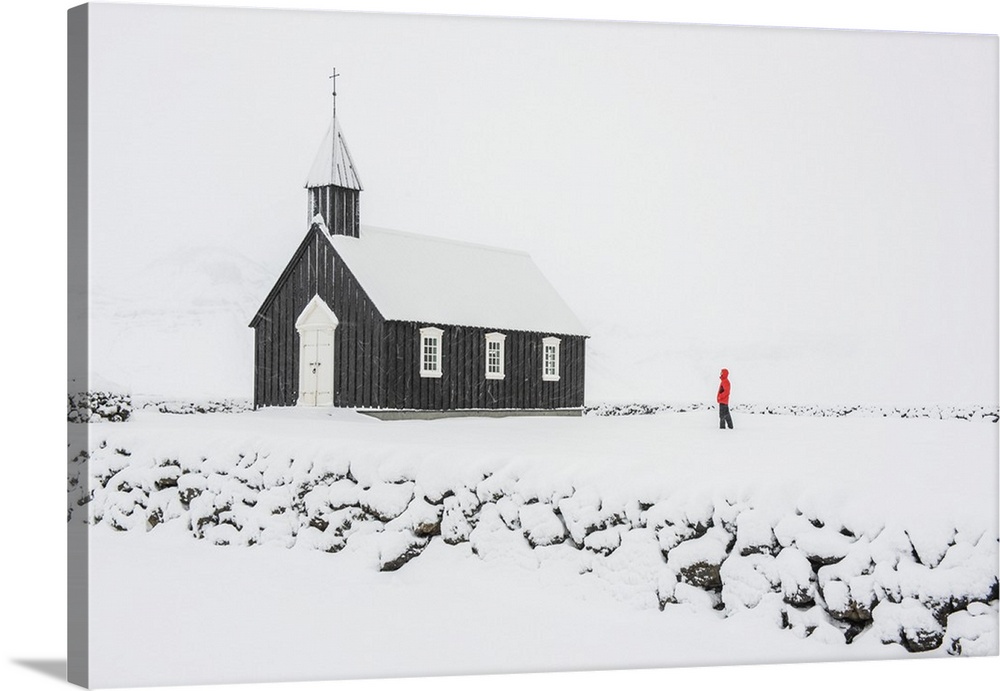 Budir, Snaefellsnes Peninsula, Western Iceland, Iceland. One person with red coat watching the black church under a snow s...