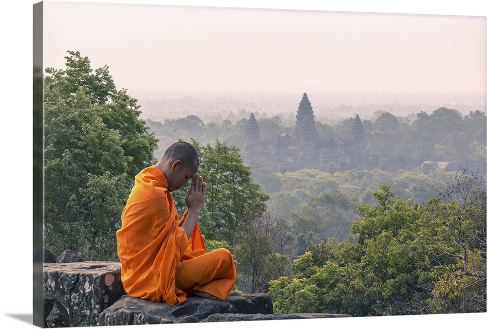 Cambodia, Siem Reap, Angkor Wat complex. Monk meditating with Angor wat temple in the background (MR)