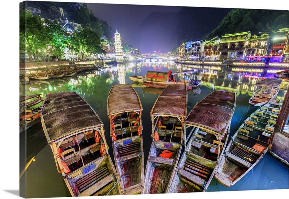 China, Hunan province, Fenghuang, traditional bamboo rafts and riverside houses reflecting in the river by night.