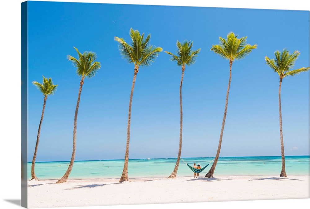 Juanillo Beach (playa Juanillo), Punta Cana, Dominican Republic. Couple relaxing on a hammock on a palm-fringed beach (MR).