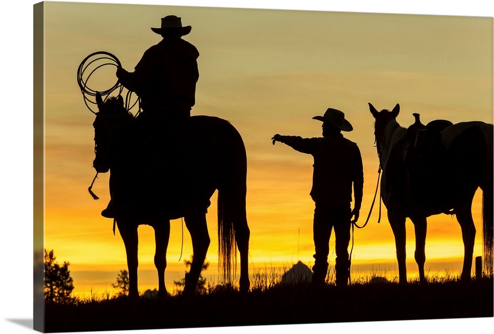 Cowboys and horses in silhouette at dawn on ranch, British Colombia, Canada.