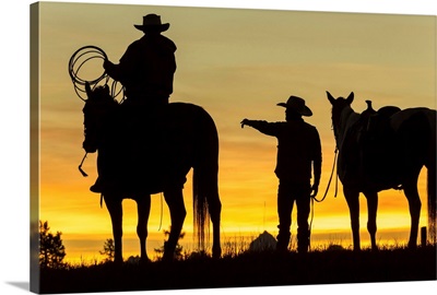 Cowboys and horses in silhouette at dawn on ranch, British Colombia, Canada
