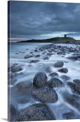 Dunstanburgh Castle at dawn from Embleton Bay, Northumberland, England