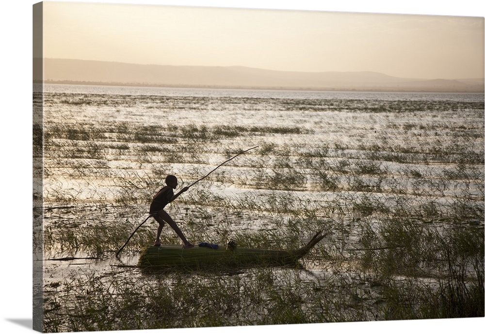 Ethiopia, Lake Awassa. A young boy punts a traditional reed Tankwa through the reeds.