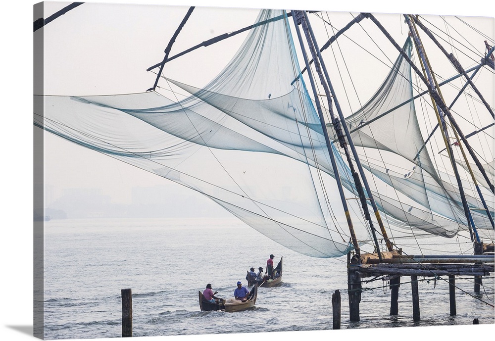 India, Kerala, Cochin - Kochi, Fort Kochi, Fishermen in dug out canoes pass under Chinese fishing nets