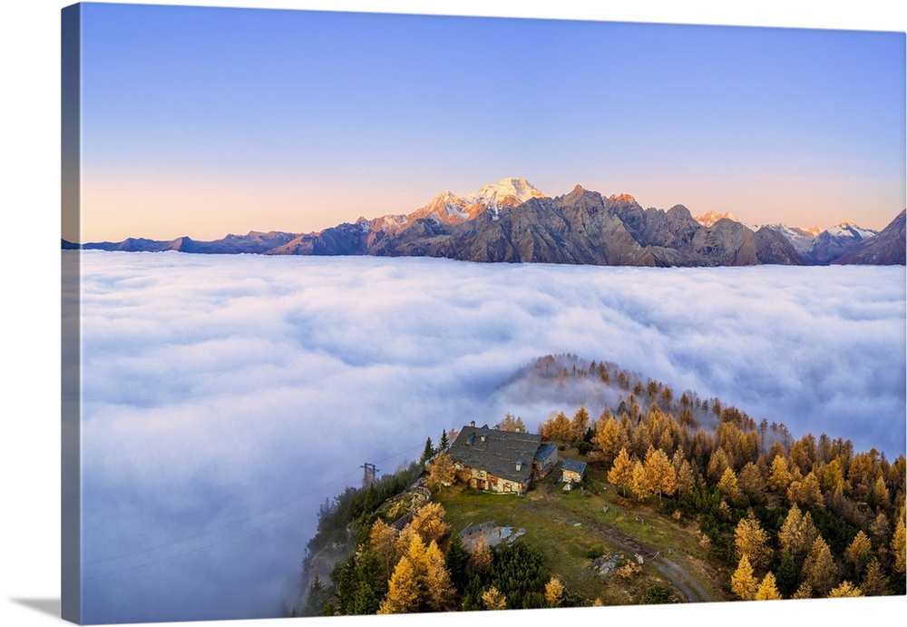 Fog covers the Valmalenco (Val Malenco) with the mountain range of Disgrazia illuminated by sunrise in the background and ...