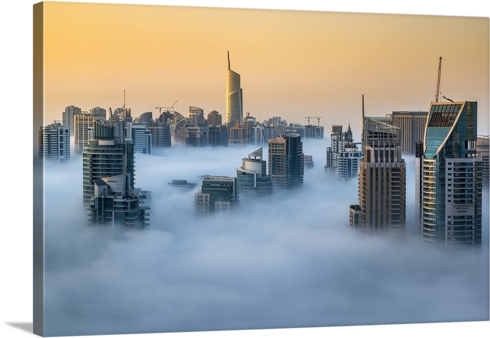 Foggy sunrise with Dubai Marina's skyscrapers towering over the low clouds, Dubai, United Arab Emirates.