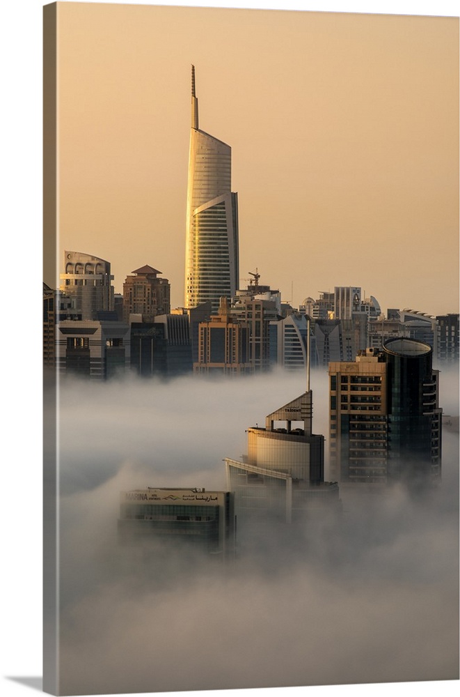 Foggy sunrise with Dubai Marina's skyscrapers towering over the low clouds, Dubai, United Arab Emirates.