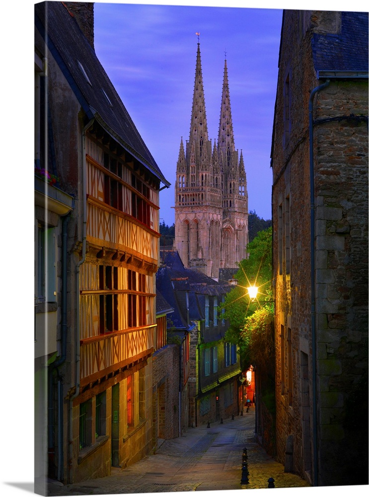 France, Brittany, Finistere, Quimper, view down cobbled street to Saint Corentin cathedral at dusk.