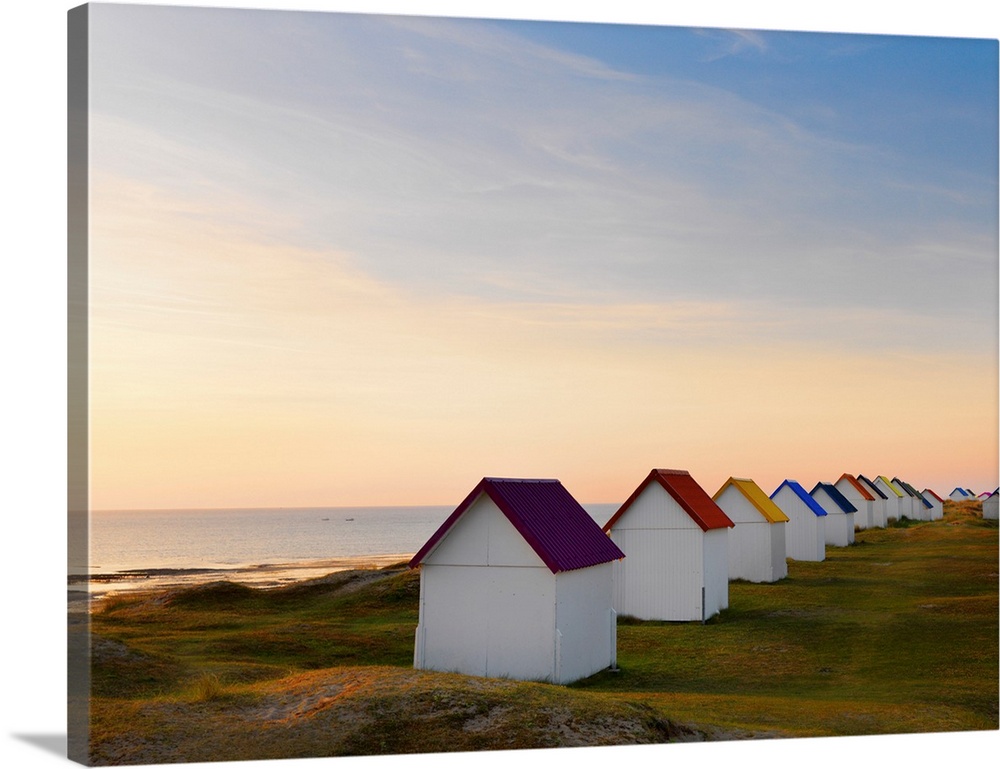 France, Normandy, Gouville Sur Mer, colourful beach huts at dusk.