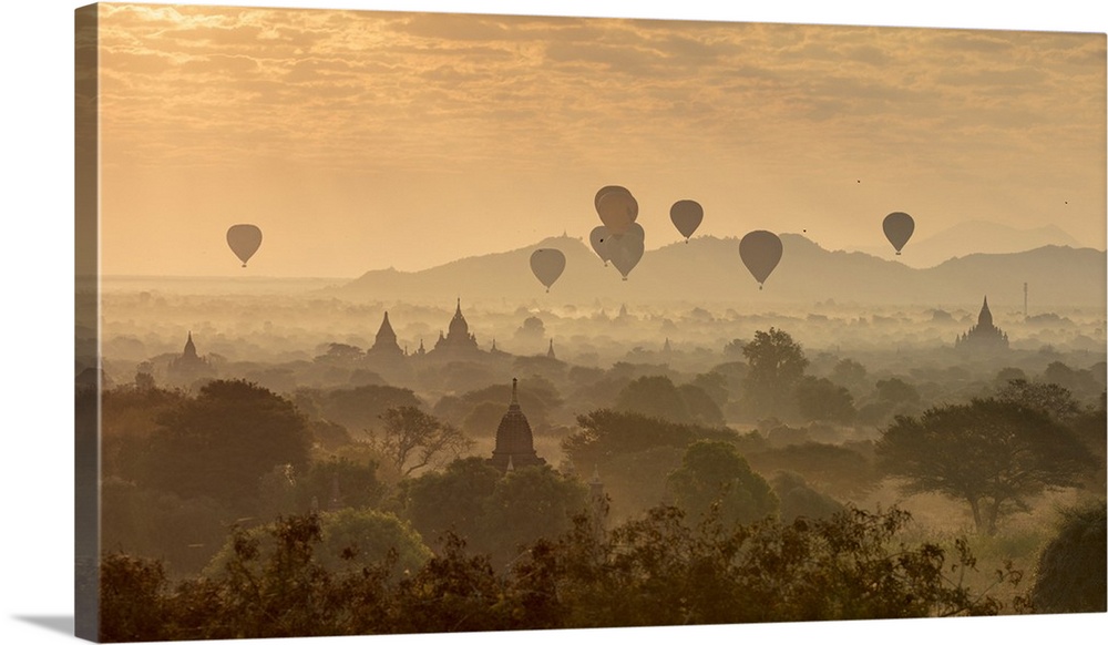 Hot air balloons fly over the temples of Bagan at sunrise on a misty morning, Myanmar.