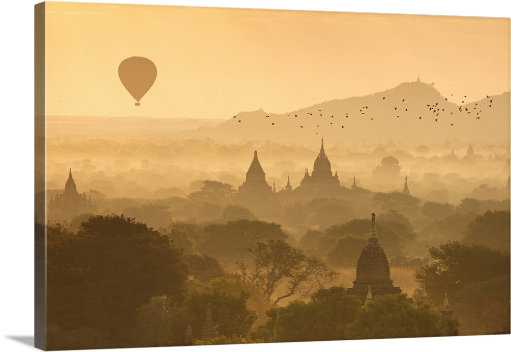 Hot air balloons fly over the temples of Bagan at sunrise on a misty morning, Myanmar.