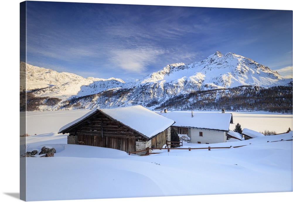 Huts and mountains covered in snow at sunset Spluga Maloja Canton of Graubunden Engadin Switzerland.