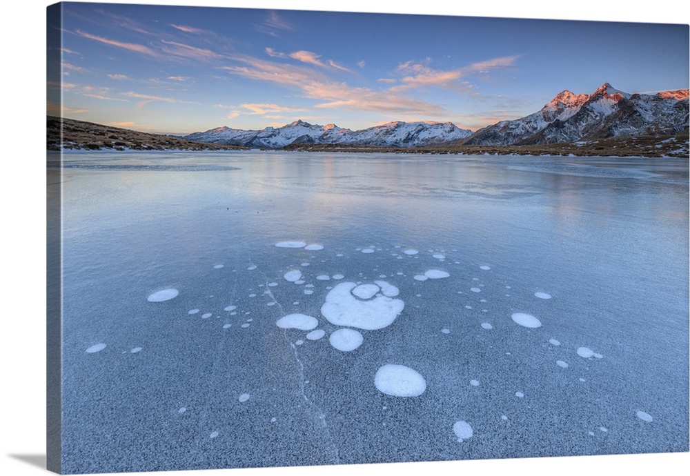 Ice bubbles on the frozen surface of Andossi Lake at sunrise Spluga Valley Valtellina Lombardy Italy Europe.