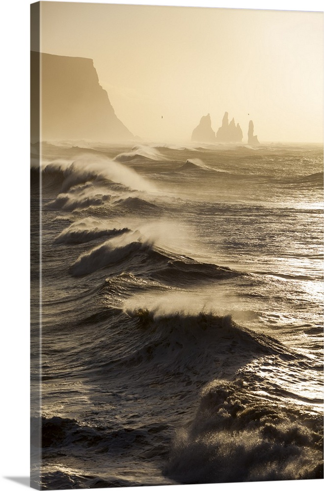 Iceland, Reynisfjara. Waves breaking on Reynisfjara beach, with the Reynisdrangar sea stacks on the horizon.