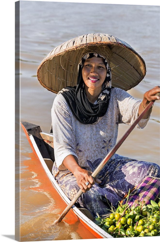 Indonesia, South Kalimatan, Lok Baintan. A woman in a wide-brimmed hat rows her small wooden boat at a floating market on ...