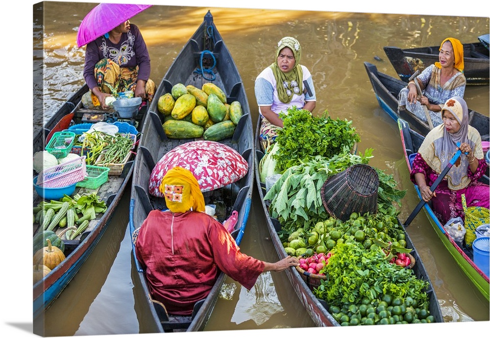 Indonesia, South Kalimatan, Lok Baintan. Market vendors pause to chat at a picturesque floating market on the Barito River.